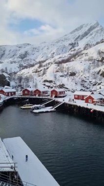 Geleneksel kırmızı ve sarı ahşap evler, küçük balıkçı köyü Nusfjord, Lofoten adaları, Norveç, Avrupa 'da. Balıkçı tekneli fiyort