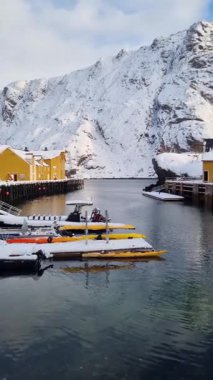 Geleneksel kırmızı ve sarı ahşap evler, küçük balıkçı köyü Nusfjord, Lofoten adaları, Norveç, Avrupa 'da. Balıkçı tekneli fiyort
