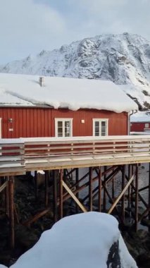 Norveç 'in Lofoten adalarındaki karlı balıkçı köyünün ahşap kırmızı evi kışın kaplıydı.