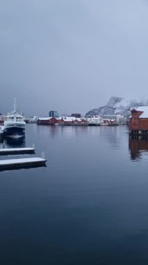 Svolvaer harbor panorama with boats, traditional and modern buildings, Snowy mountain on horizon. Lofoten islands, Norway.