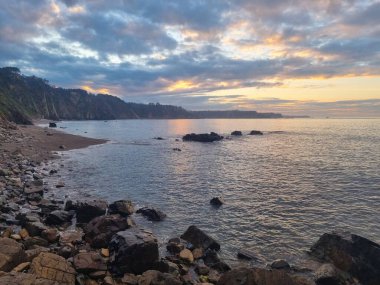 İspanya 'nın kuzey Atlantik kıyılarındaki kayalıkların tepesinden gün batımında sisli bir atmosferle panoramik manzara