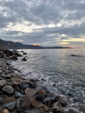 İspanya 'nın kuzey Atlantik kıyılarındaki kayalıkların tepesinden gün batımında sisli bir atmosferle panoramik manzara