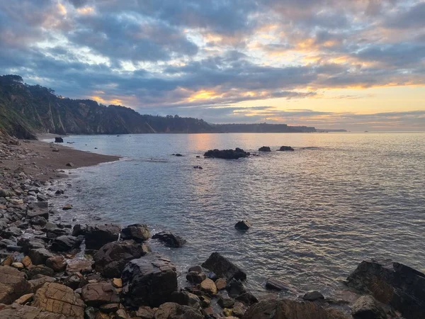 İspanya 'nın kuzey Atlantik kıyılarındaki kayalıkların tepesinden gün batımında sisli bir atmosferle panoramik manzara