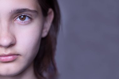 Esmer bir kızın yüzünün yarısı koyu kahverengi gözlü ve kalın kaşlı. Bob saç kesimi, kısa saç.