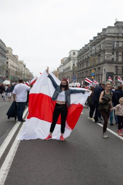 Genç ve güzel bir kadın yolda tıbbi bir maske takıyor. Büyük beyaz bir bayrak taşıyor. Ağustos 2020 Belarus Minsk