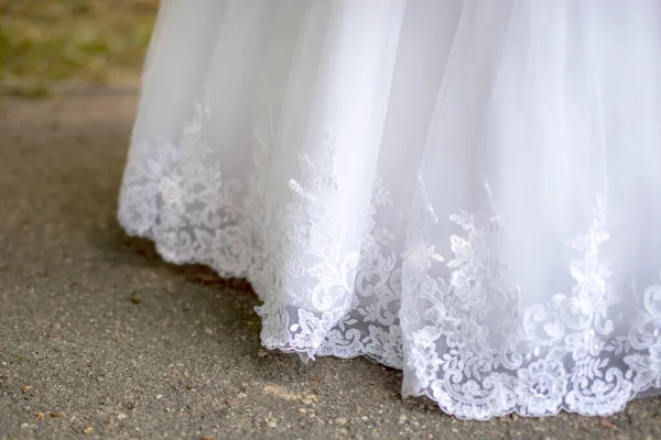 La parte inferior de un hermoso vestido de novia blanco esponjoso. Tradiciones matrimoniales. Asfalto gris. —  Fotos de Stock