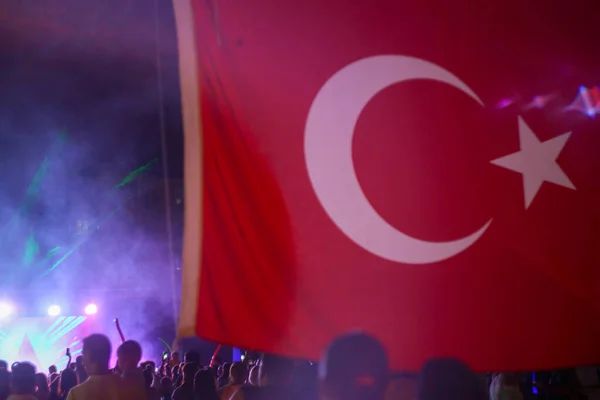 Большой красивый флаг Турции, и на фоне концерта с большим количеством людей. Ночные прогулки в отеле. — стоковое фото
