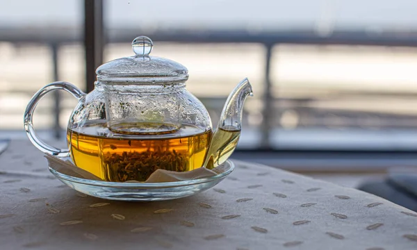 Transparante theepot met hete groene natuurlijke helende thee. Groot raam en balkon. — Stockfoto