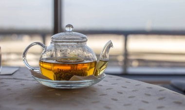 Yeşil doğal şifalı çay ile şeffaf çaydanlık. Geniş pencere ve balkon.