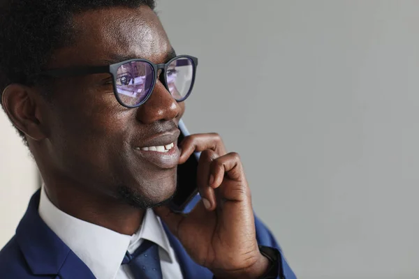 携帯電話で話している間に笑顔の眼鏡でアフリカの若いビジネスマンのクローズアップ — ストック写真