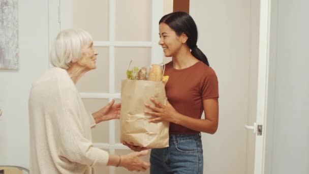 Junge Pflegerin Bringt Tüte Mit Produkten Zur Seniorin Nach Hause — Stockvideo