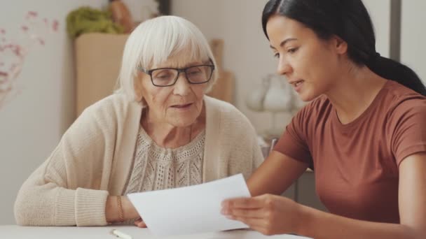 Young Female Social Worker Asian Ethnicity Explaining Document Elderly Caucasian — Vídeo de Stock