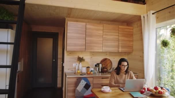 在乡间别墅的厨房桌上 一个年轻的高加索女人在笔记本电脑上浏览互联网 把镜头放大 — 图库视频影像