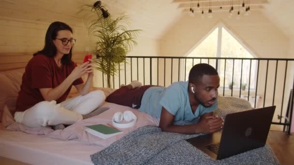 Young Black Man Wireless Earphones Lying Bed Talking Online Web — Stock Video