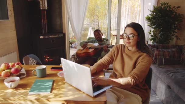 Junge Kaukasische Frau Arbeitet Laptop Während Ihr Afroamerikanischer Mann Ferienhaus — Stockvideo