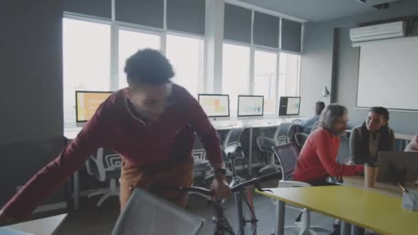 Młody Przystojny Mieszane Wyścigu Człowiek Spaceru Przez Biuro Rowerem Laptopem — Wideo stockowe