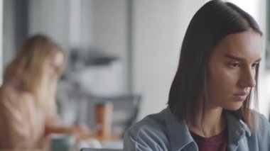 Ofiste çalışırken kameraya bakıp mutlu bir şekilde gülümseyen günlük giysili beyaz bir kadının göğüs görüntüsü.