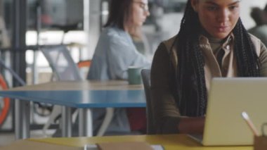 Ofis masasında dizüstü bilgisayarla çalışan Afro-Amerikan iş kadınının portre fotoğrafını kaldır ve kameraya bak ve gülümse.