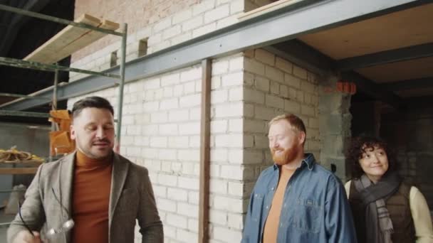 Male Architect Walking Cheerful Couple Unfinished Flat Showing Them Something — Stock Video