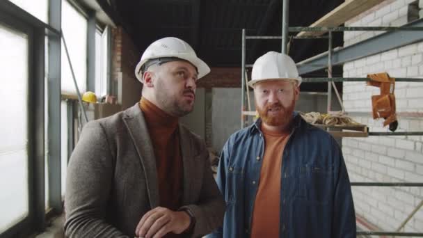헬멧을 직업적 건축가가 미완성 아파트에 클립보드 위에서 손님에게 무엇인가를 설명하는 — 비디오