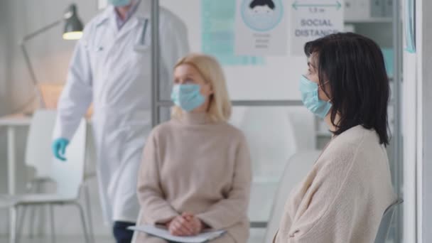 Zwei Frauen Mit Schutzmasken Sitzen Wartezimmer Der Arztpraxis Während Ein — Stockvideo