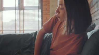 Genç Asyalı bir kadının sabah yatağında uyanırken çekilmiş fotoğrafı. Akıllı telefon alıp sosyal medyayı kontrol ediyor.