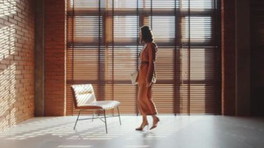 Genç, zarif Asyalı iş kadını ofise geliyor, sandalyeye oturuyor ve dizüstü bilgisayarla çalışmaya başlıyor.