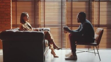 Genç, şık Asyalı kadın ve elinde kahve fincanları olan Afro-Amerikalı adamdan uzaklaşın ve ofiste iş tartışması yapın.