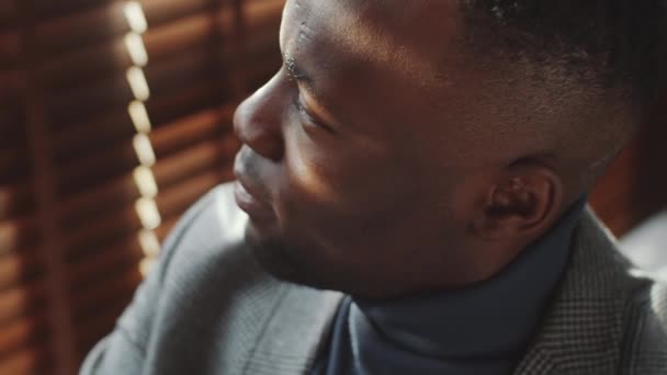 窓を通して見て その後 カメラのためにポーズを取るハンサムなアフリカ系アメリカ人のビジネスマンの高角度のクローズアップショット — ストック動画