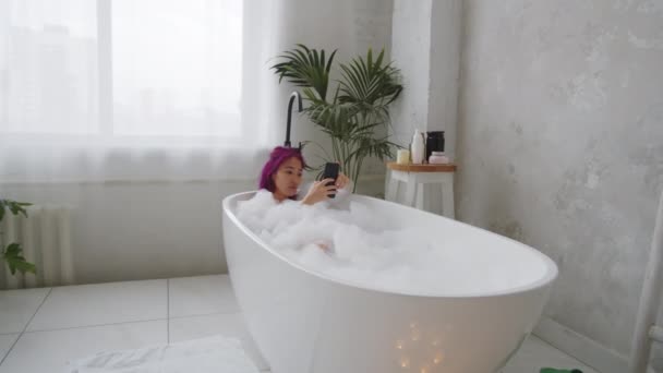 Zoom Shot Young Asian Woman Pink Hair Lying Bathtub Browsing — Stock Video