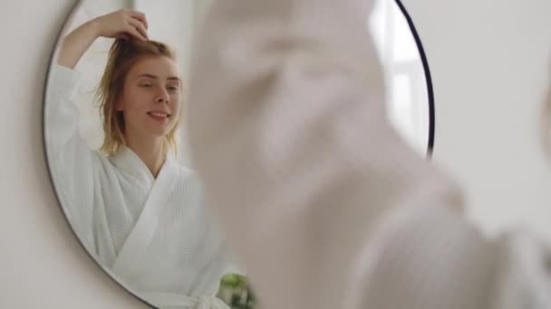 Mladá Blondýnka Županu Úsměvem Sušení Vlasů Fénem Před Koupelnou Zrcadlo — Stock video