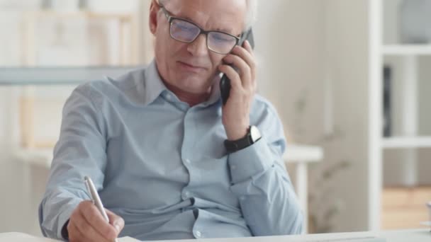 Senior Affärsman Sitter Vid Skrivbordet Kontoret Pratar Smartphone Håller Pennan — Stockvideo