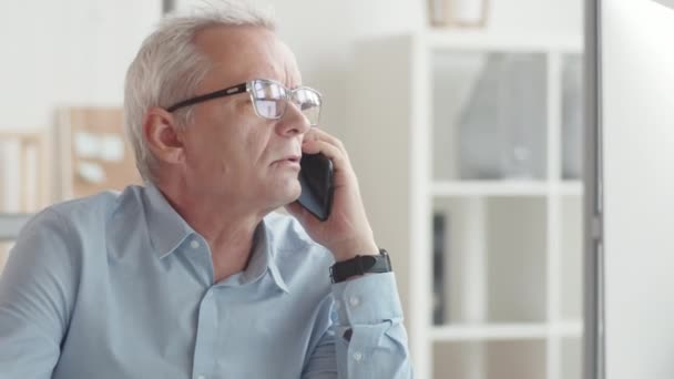 Senior Affärsman Sitter Vid Skrivbordet Kontoret Pratar Smartphone Håller Pennan — Stockvideo