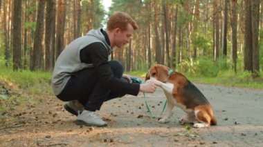 Yaz günü parkta antrenman yaparken beyaz bir adamın tasmalı av köpeğiyle oynaması.