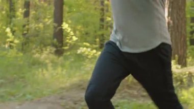 Spor kıyafetleri içinde genç yakışıklı bir adam sabah antrenman yaparken parkta koşuyor.