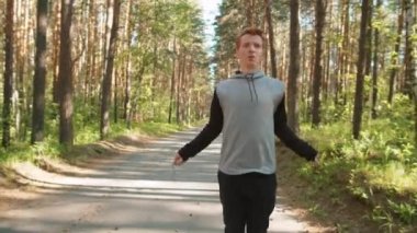 Spor giyimli bir gencin sabah spor yaparken parkta ip atlarken ki görüntüsü.