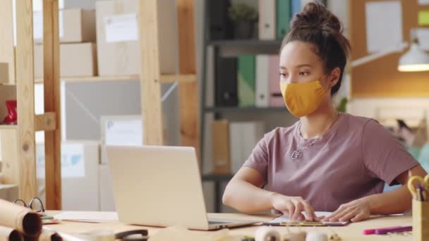Jovem Gerente Feminina Mestiça Máscara Protetora Digitando Laptop Tomando Notas — Vídeo de Stock