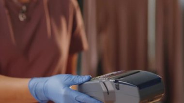 Müşteriler kredi kartıyla ödeme yaparken, tanımadığımız kasiyerlerin ellerinde koruyucu eldivenler tutarken yakın plan çekimleri.