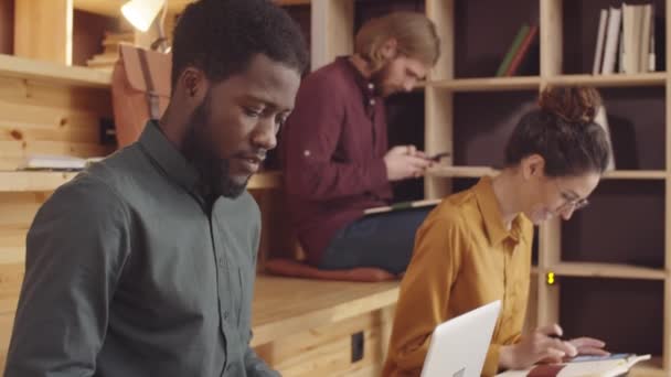 Medium Tilting Shot Three Cheerful Diverse Young People Sitting Benches — Stockvideo