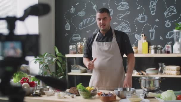 Chef Masculino Delantal Mostrando Los Ingredientes Hablando Cámara Mientras Graba — Vídeos de Stock