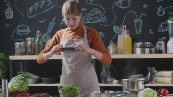 Joven Blogger Delantal Fotografiando Verduras Frescas Mesa Cocina Con Smartphone — Vídeos de Stock