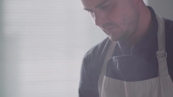 在厨房的炉灶上做饭时 把男性厨师在油锅里腌制热食的特写镜头倾斜下来 — 图库视频影像