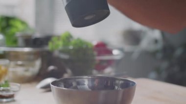 Tanınmayan bir adamın elleri, elektrikli öğütücüden metal kaseye kara biber dökerken yakın çekim.