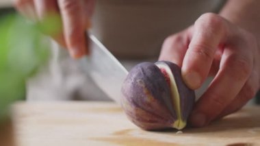 Bıçakla taze incir kesen tanınmayan erkek şefin yakın çekimleri.