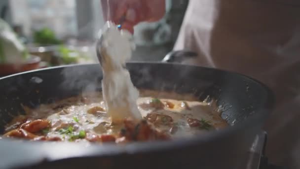 프라이팬에서 요리하는 뜨끈하게 닭고기 스튜에 치즈를 첨가하는 요리사의 — 비디오