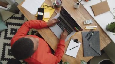 Afro-Amerikalı iş adamının bilgisayarında daktilo yazarken, akıllı telefon kullanırken, belgelerle çalışırken ve ofis masasında çay içerken zaman aşımı görüntüsü.