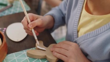 Paskalya zanaatı yaparken küçük bir kızın tahta tavşanın kafasına boya çizerken yakın plan resmini çek.