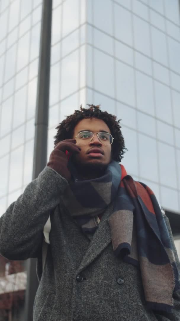Pionowe Ujęcie Młodego Afroamerykanina Wykonującego Telefon Mówiącego Stojącego Świeżym Powietrzu — Wideo stockowe