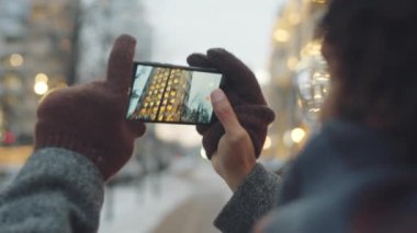 Omzunun üzerinden, Afro-Amerikalı bir adamın şehir binasının ve caddenin fotoğrafını çektiği seçici bir fotoğraf.
