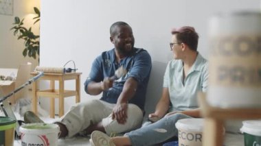 Afro-Amerikalı neşeli bir erkek ve beyaz bir kadının portresi. Odada oturmuş, tadilat altında sohbet ediyor ve kamera karşısında birlikte poz veriyor ve gülümsüyor.